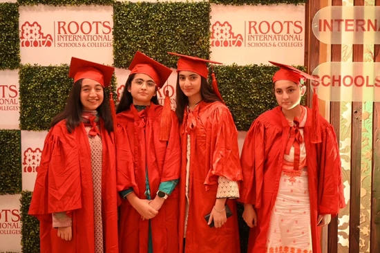 Four Roots International students celebrating their graduation in red caps and gowns